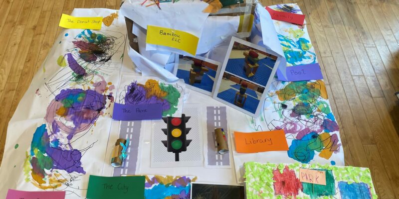 NSW - This collaborative arts project, created by our Three Year Old Kindergarten community at Bambou ELC, uses mixed media to visually represent our community and neighbourhood. Photography, 3D construction, drawing, sculpture and painting have been used to model and map out places which are of significance to the children’s sense of wellbeing and safety. This work captures the perspectives of the children and their families’ and tells a narrative about which places in our community and neighbourhood we feel are important to us and that we are grateful for having. Many of the children created their Kinder and home and places that they enjoy visiting with their family including parks, playgrounds, swimming pools, shops, libraries and the city. The children’s sense of understanding about how their community and neighbourhoods are connected was extended through the time they spent coming together with their peers to arrange and geographically map out the places and activities they had created into a single model. Layers of places of individual significance to the children and families are interconnected by models of cars which are the main form of transport used among our community. These cars symbolically connect our individual and shared neighbourhoods into this representation of our community which reflects the children and our families’ sense of happiness, safety and wellbeing.