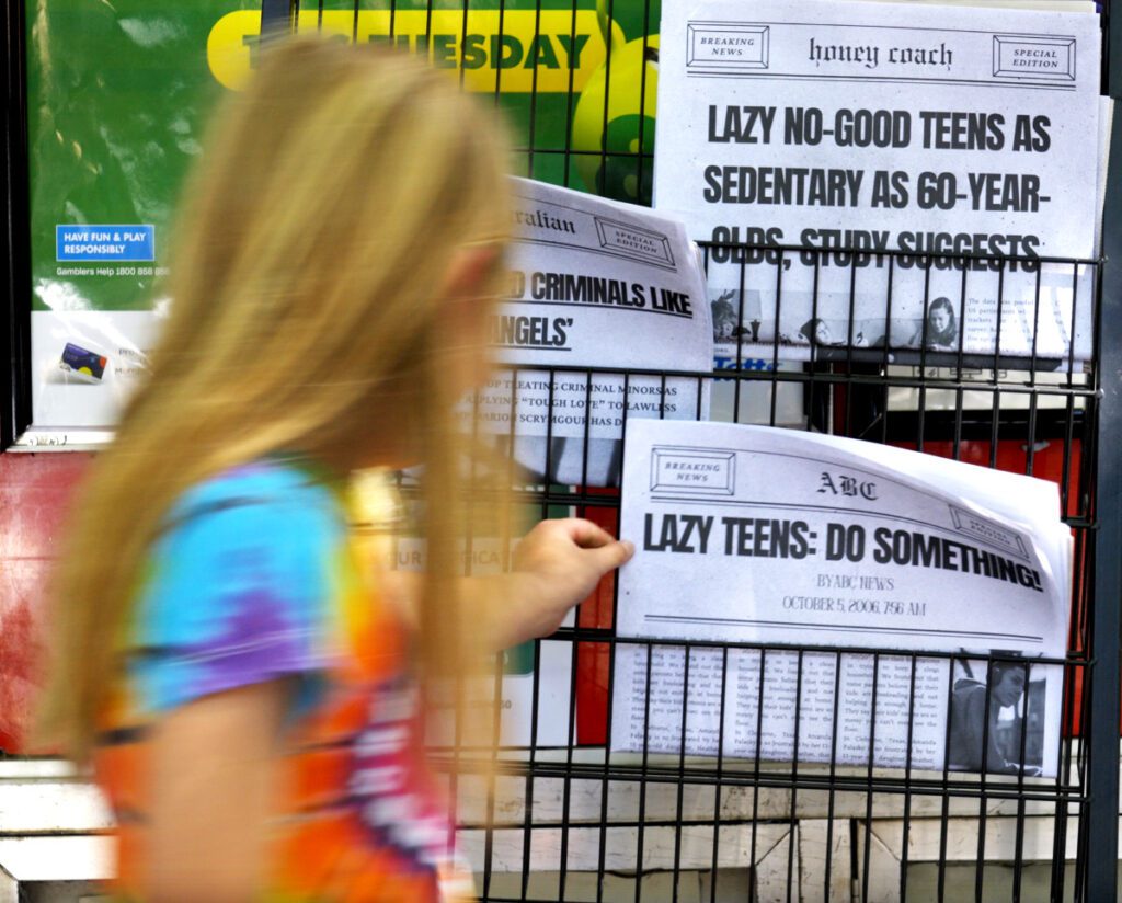 Image of young person in colourful shirt picking up a newspaper.